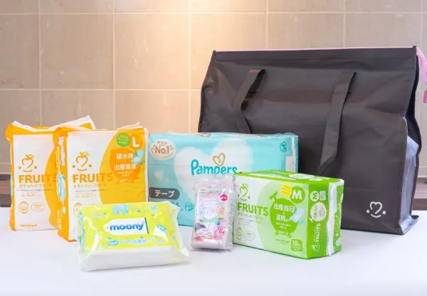 入院時に必要な消耗品をまとめたお産セット。おむつ（パンパース）、おしりふき、産褥パッド、アメニティ、そして黒い大きなバッグなど、様々なベビー用品や産後用品が写っている。
