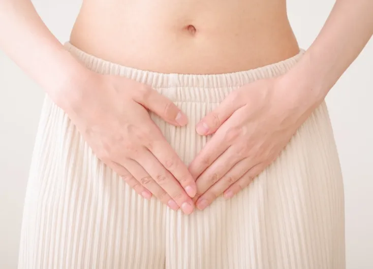 女性がお腹に手を当てている様子""