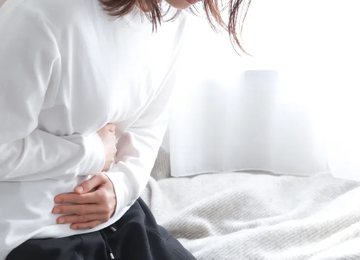 女性がカレンダーまたは基礎体温表をペンで指し示しているクローズアップ。月経周期の管理や排卵日の特定、または診療日の確認の様子。